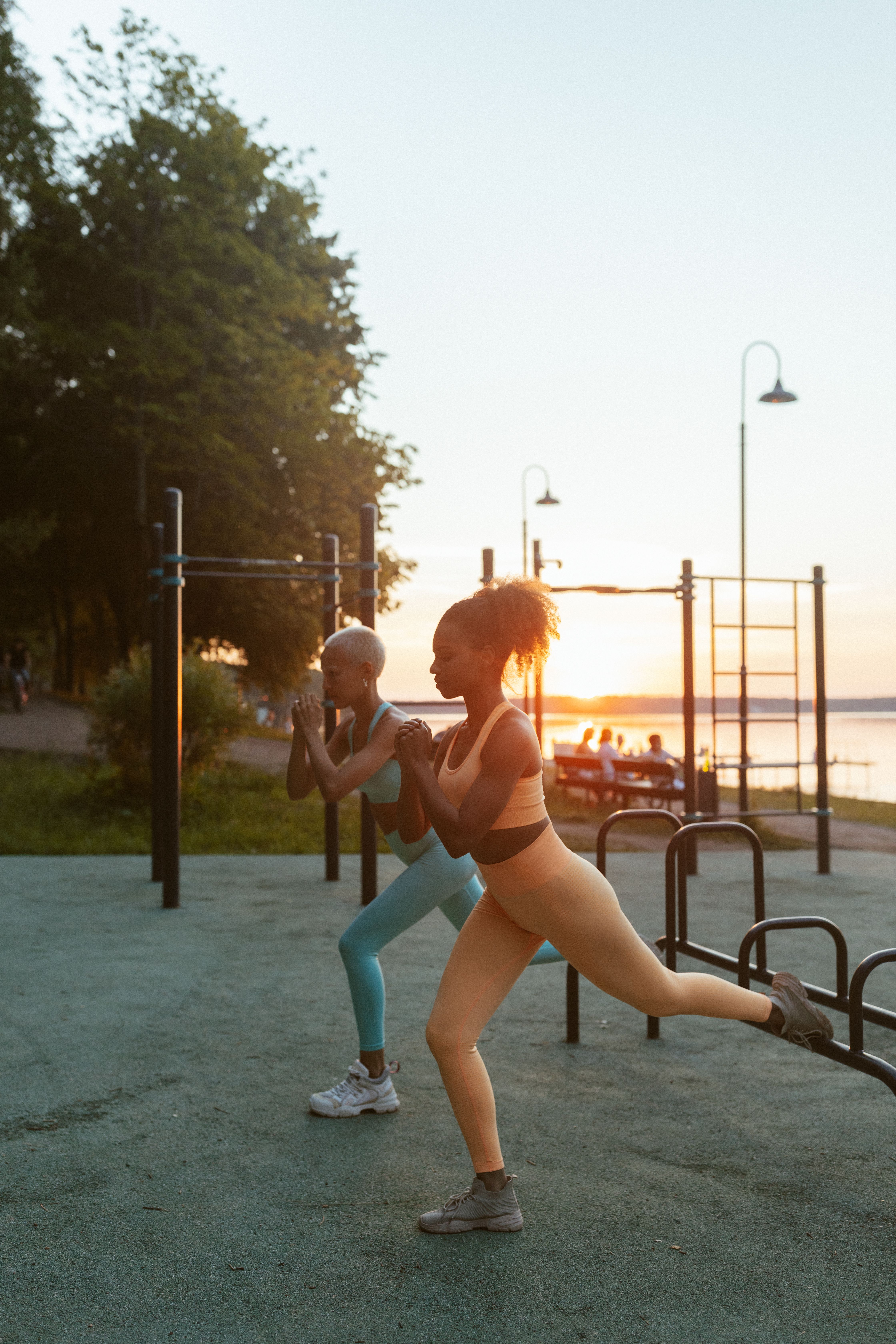 Zwei Personen trainieren bei Sonnenuntergang an einer Outdoor-Fitnessstation im Park